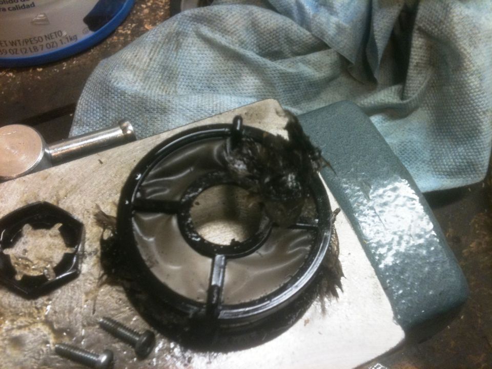 Dirty oil filter housing with debris and screws on a workbench