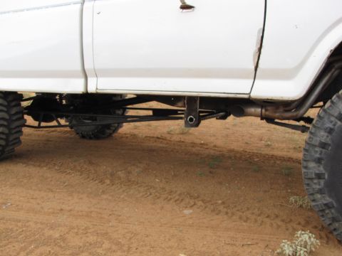 1995 Ford Bronco - Side view of a white pickup truck's rear suspension system and large tires.
