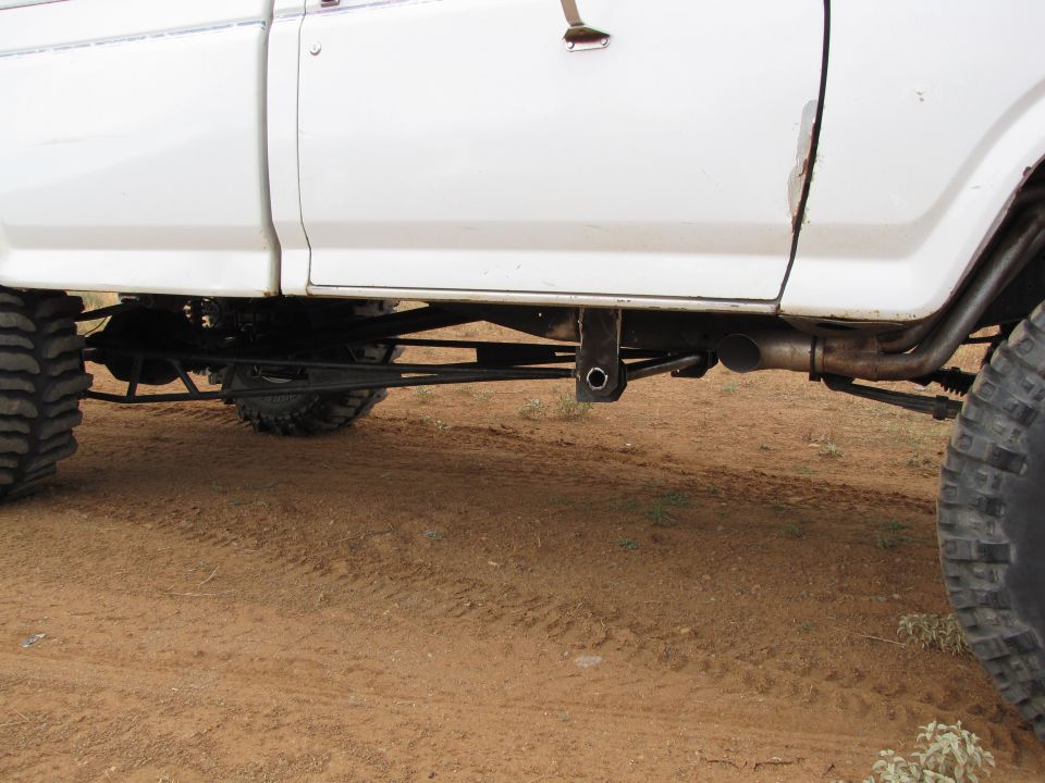 White truck rear suspension with large tires and custom linkage
