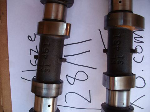 1994 Mazda MX-6 - Close-up of two engine camshafts with stamped part numbers and handwritten annotations on paper.