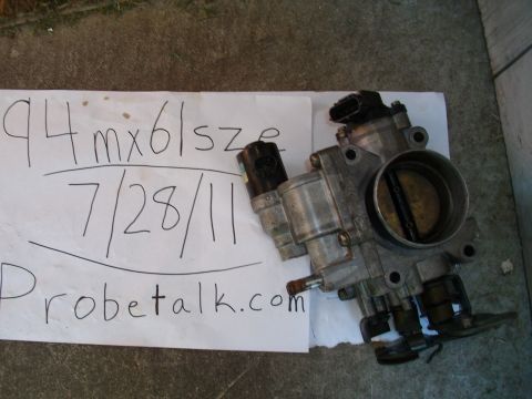1994 Mazda MX-6 - A throttle body is shown next to a paper with '94 MX6' and a date written on it.