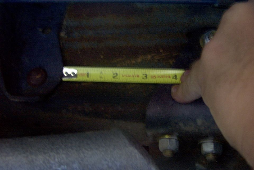 Measuring suspension component with a tape measure showing 3 inches