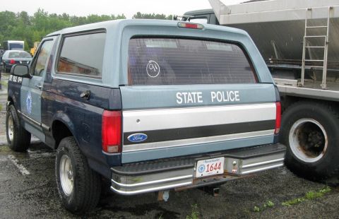 1991 Ford LTD Crown Victoria - A Ford Bronco, marked "STATE POLICE", is seen from the rear, parked next to a large truck.