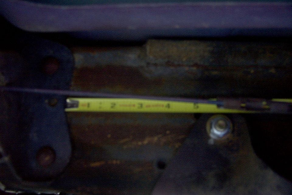 Yellow measuring tape showing inches on a rusty metal surface with bolts