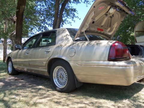 2000 Mercury Grand Marquis - A gold sedan is parked outdoors with its trunk open, revealing some interior lighting modifications.