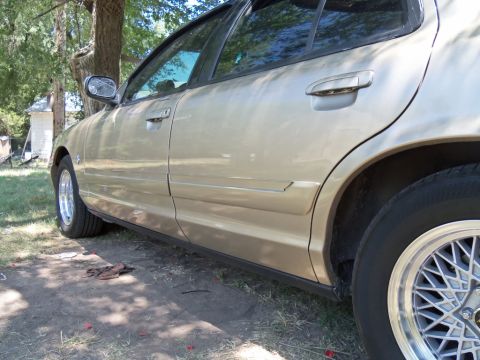 2000 Mercury Grand Marquis - Side view of a gold sedan, highlighting the door trim and body lines.