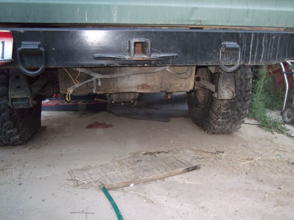 Rear view of a vehicle showing the bumper, fuel tank, and tires