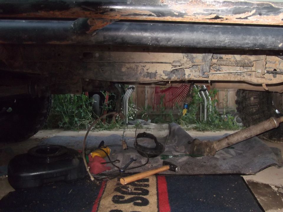 underbody of a vehicle with tools and parts laid out for repair