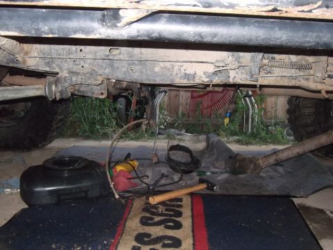 1989 Ford Bronco - Tools and a drain pan are laid out beneath the chassis of a vehicle.