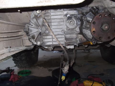 1989 Ford Bronco - Transfer case and driveshaft assembly shown from underneath a vehicle. A yellow connector is attached.