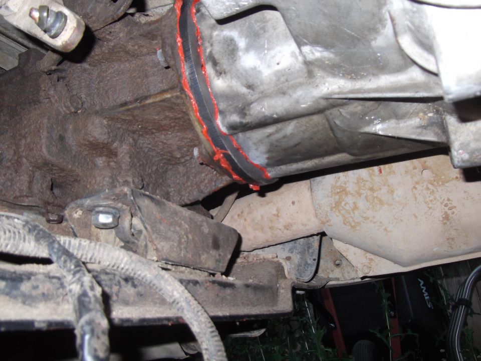 close-up of vehicle transmission with red sealant and exhaust pipe