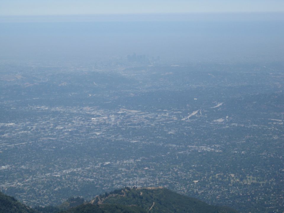 Hazy telephoto view of a distant downtown skyline from a mountain overlook