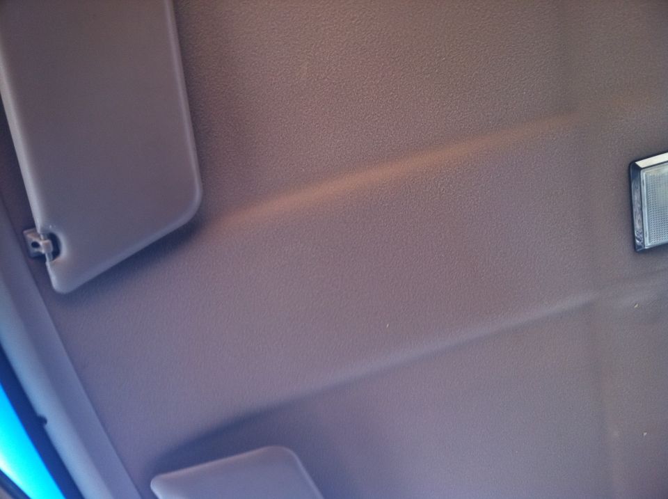 Interior ceiling with sun visors and a light fixture, brown textured fabric