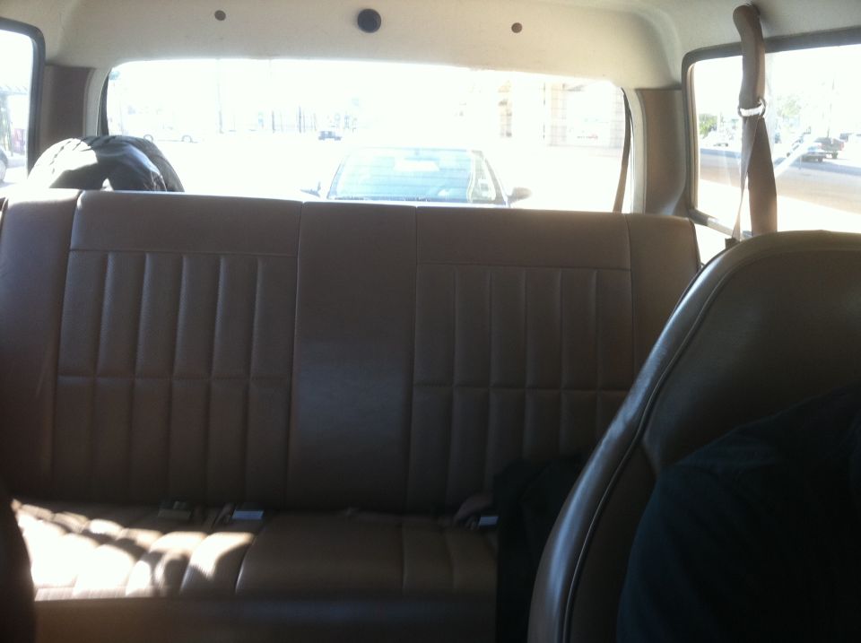 Rear bench seat and interior of a vehicle, looking out the back window at another car