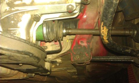 1991 Ford Festiva - Underside view of a vehicle's driveshaft and suspension components, with a prominent green boot on the driveshaft.