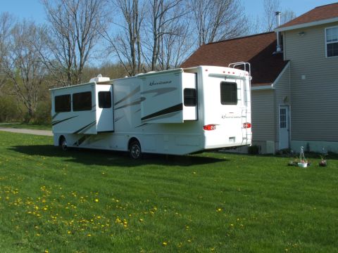 2007 Ford Supercrewzer - Motorhome with "Hurricane" badging is parked on a grassy lawn next to a house.