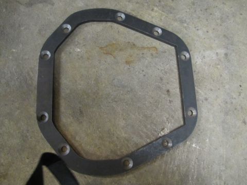 1995 Ford Bronco - A differential cover gasket is pictured on a concrete surface. The part has a distinctive octagonal shape with bolt holes around the perime…