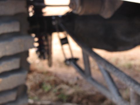 1995 Ford Bronco - The underside of a vehicle is shown, focusing on the rear tire and suspension system.