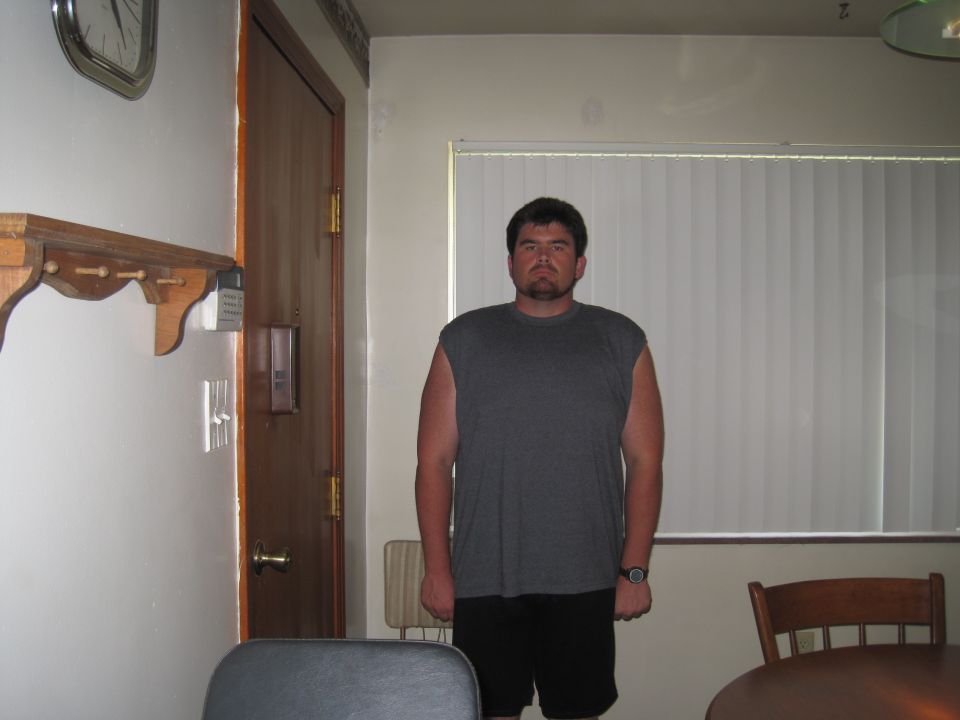 Man in a gray sleeveless shirt and black shorts standing indoors