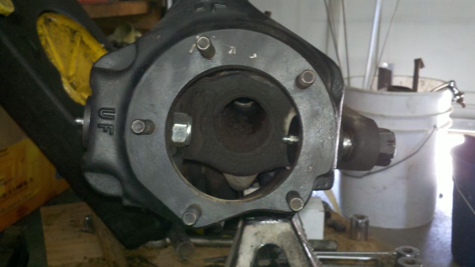 Close-up of a front axle differential housing with 'UF' cast into it, sitting on a jack stand