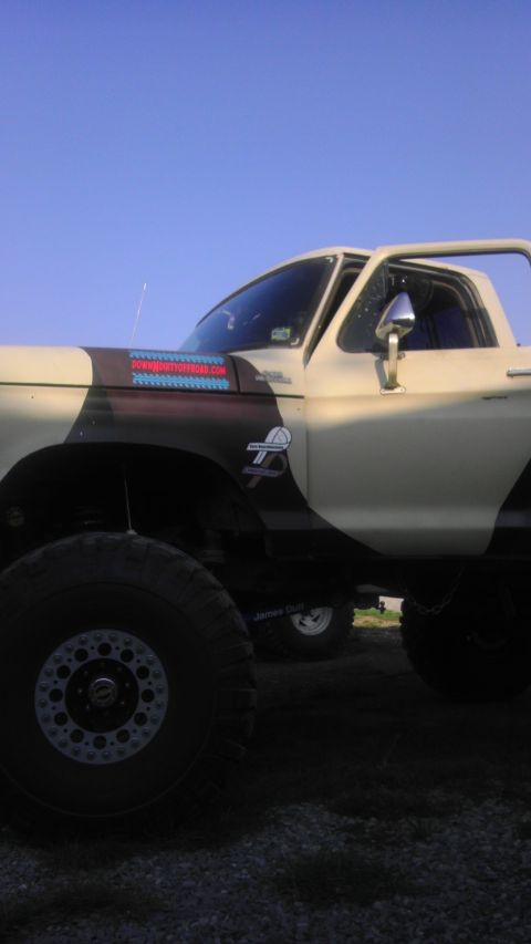 1989 Ford Bronco - A lifted 1978 Ford Bronco with custom paint and large off-road tires is parked under a clear blue sky.
