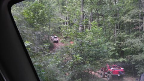 1989 Ford Bronco - Off-road vehicles navigate a steep, wooded trail during an outdoor excursion.