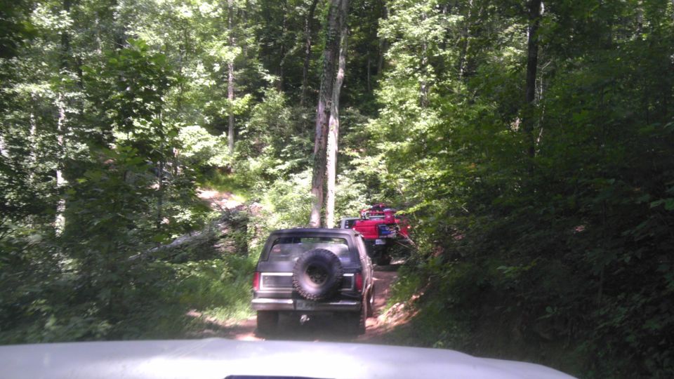 Black Ford Bronco with spare tire on rear door, driving on dirt road