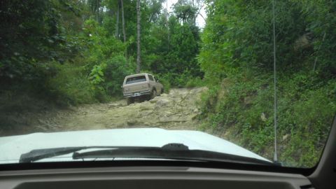 1989 Ford Bronco - 1989 Ford Bronco navigates a challenging rocky path in a wooded area.