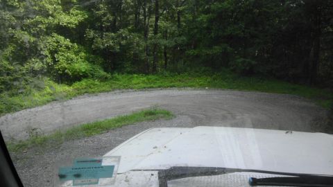 1989 Ford Bronco - Driving through a wooded area on a gravel road with a sharp curve ahead.