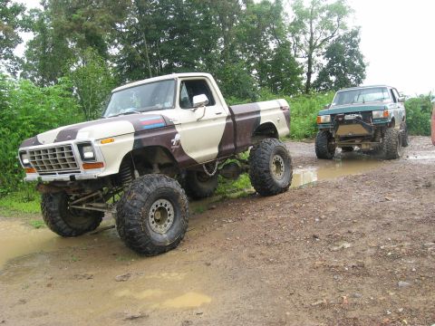 1990 Ford Bronco - A lifted 1979 Ford pickup truck with camouflage paint is seen off-road with another vehicle in the background.