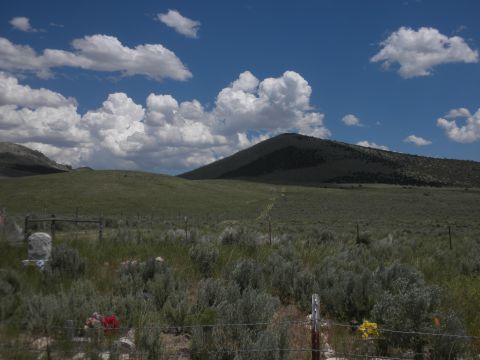 1989 Ford Bronco - A vast, open landscape under a dramatic sky, rolling green hills and sparse vegetation, with a fence line in the foreground.