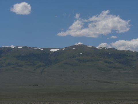 1989 Ford Bronco - A wide view of a mountain range under a partly cloudy sky, with a distant structure on the plains.