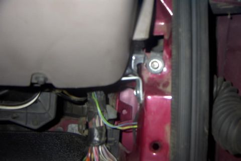 1994 Ford Bronco - Blurry close-up inside a partially disassembled vehicle showing a maroon-painted body pillar with a bolt, an exposed wiring harness with ta…