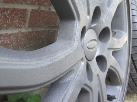 2010 Ford Fusion - A close-up view of a vehicle's wheel and tire, with a brick wall visible behind it.
