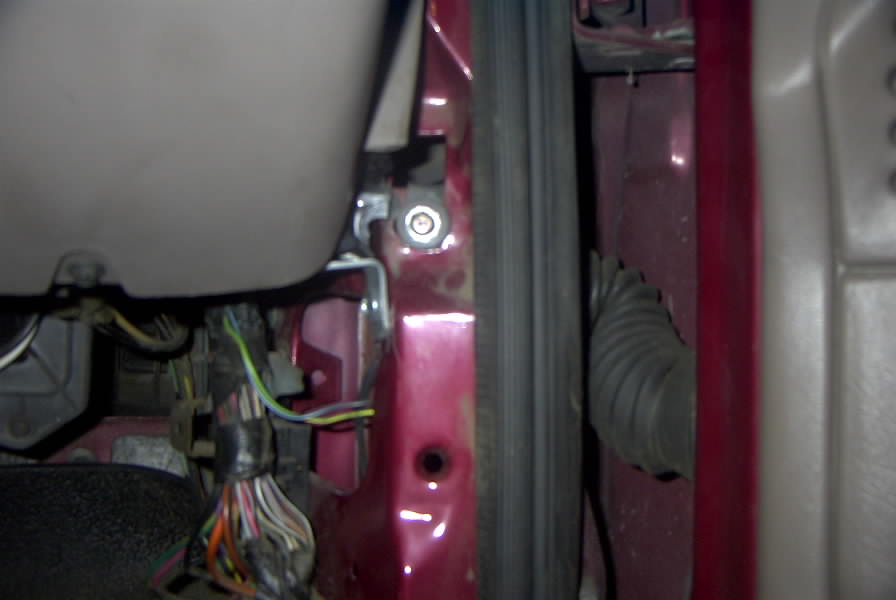 Maroon vehicle door jamb with wiring harness, striker bolt and door wiring boot exposed