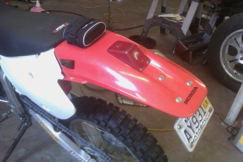 2002 Honda XR600R - The rear section of a red and white Honda dirt bike is shown, with a license plate attached to the fender.
