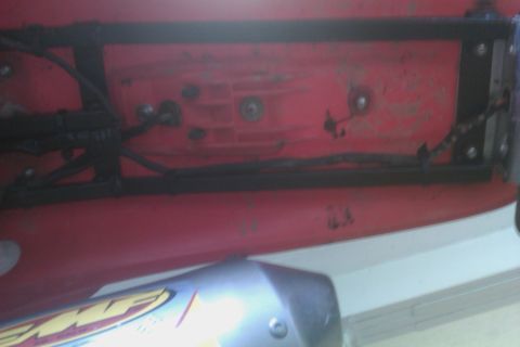 2002 Honda XR600R - Close-up of a motorcycle's exhaust pipe and frame, with visible wiring and red plastic components.