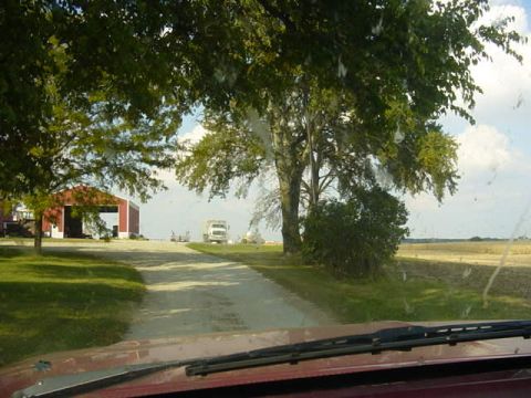 1992 Ford Bronco - A rural landscape unfolds, a barn and a distant truck, viewed from the perspective of a car.