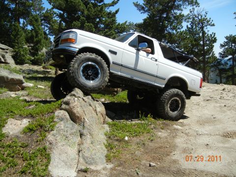 1996 Ford Bronco - 1996 Ford Bronco navigating a rocky off-road course on a sunny day.
