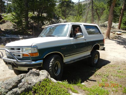 1996 Ford Bronco - 1996 Ford Bronco navigating an off-road trail in a wooded area.