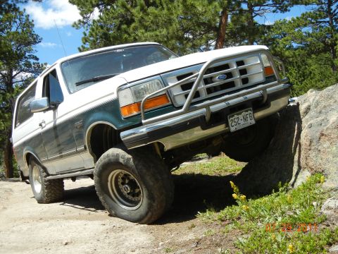 1996 Ford Bronco - This Ford Bronco is navigating a rocky trail with its front tire on a large boulder.