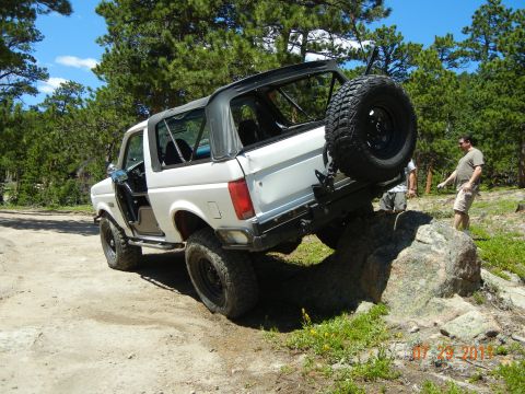 1996 Ford Bronco - White 1996 Ford Bronco with removable top is climbing over rocks on a dirt trail.