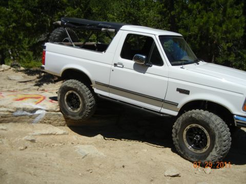 1996 Ford Bronco - This 1996 Ford Bronco is shown off-roading on a rocky trail with a soft top covering the rear bed.
