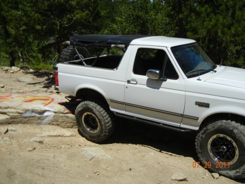 1996 Ford Bronco - This white Ford Bronco, likely from the early to mid-1990s, is equipped for off-road use with large tires and side steps.