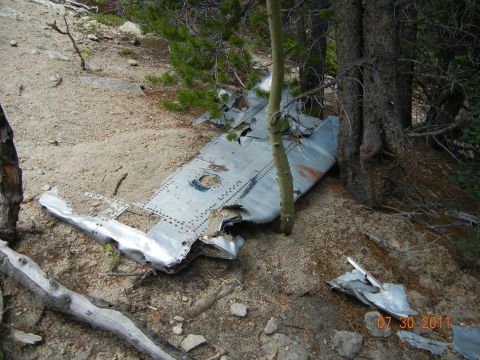 1996 Ford Bronco - Debris from an aircraft crash lies scattered amongst trees and dirt, with a date stamp of 07.30.2011 visible.