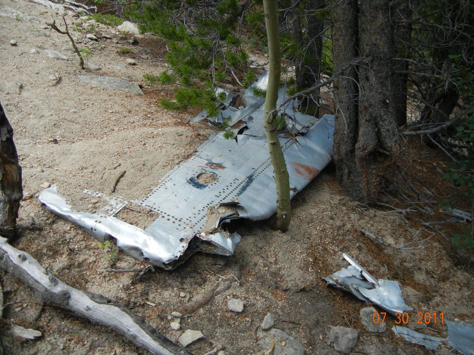 wreckage of an airplane wing and fuselage in a wooded area
