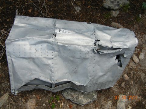 1996 Ford Bronco - A damaged section of aluminum fuselage, possibly from an aircraft, lies on the ground with visible rivets and partial text.
