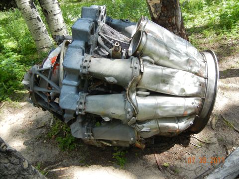 1996 Ford Bronco - This appears to be a damaged engine component, possibly from an aircraft, lying in a wooded area.
