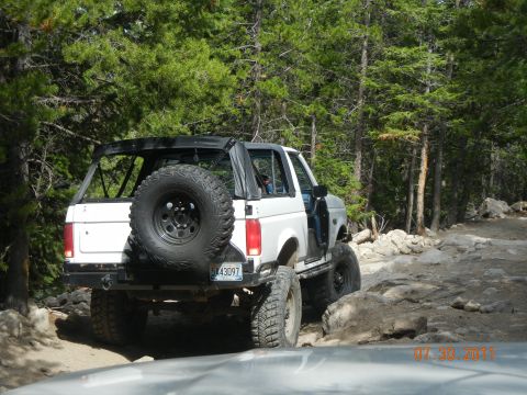 1996 Ford Bronco - A white Ford Bronco navigates a rocky trail surrounded by trees, with a date stamp of 07 30 2011 in the corner.