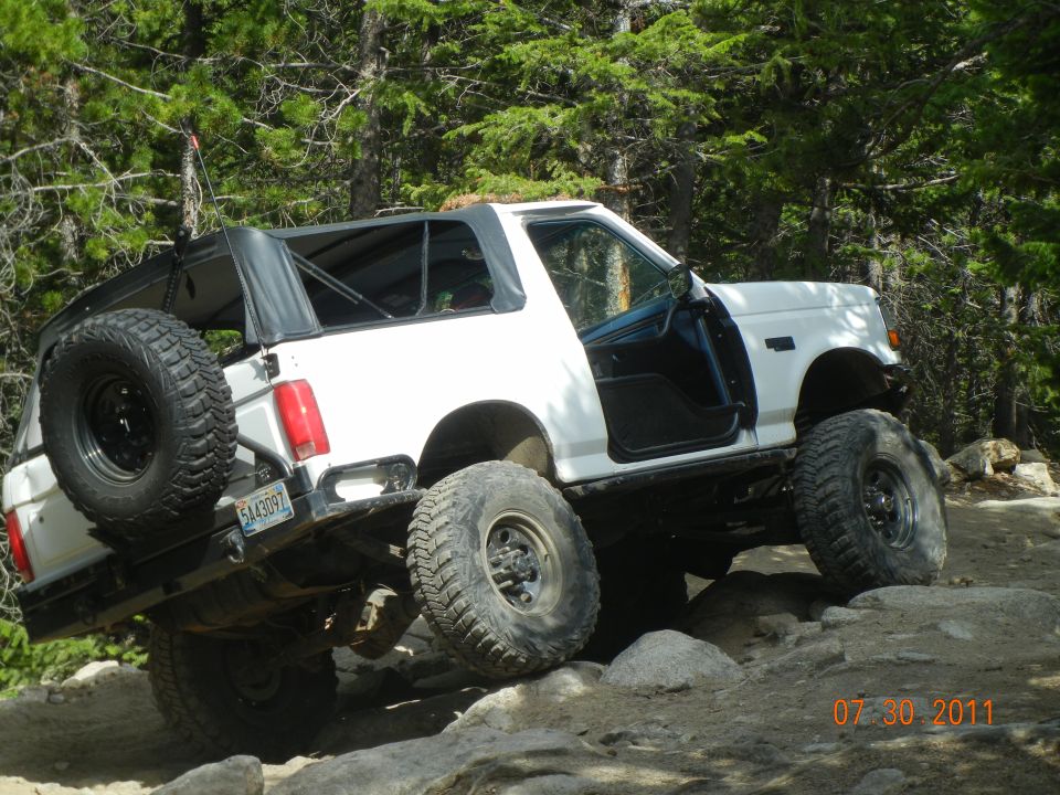 White 1996 Ford Bronco off-roading with doors removed and soft top up